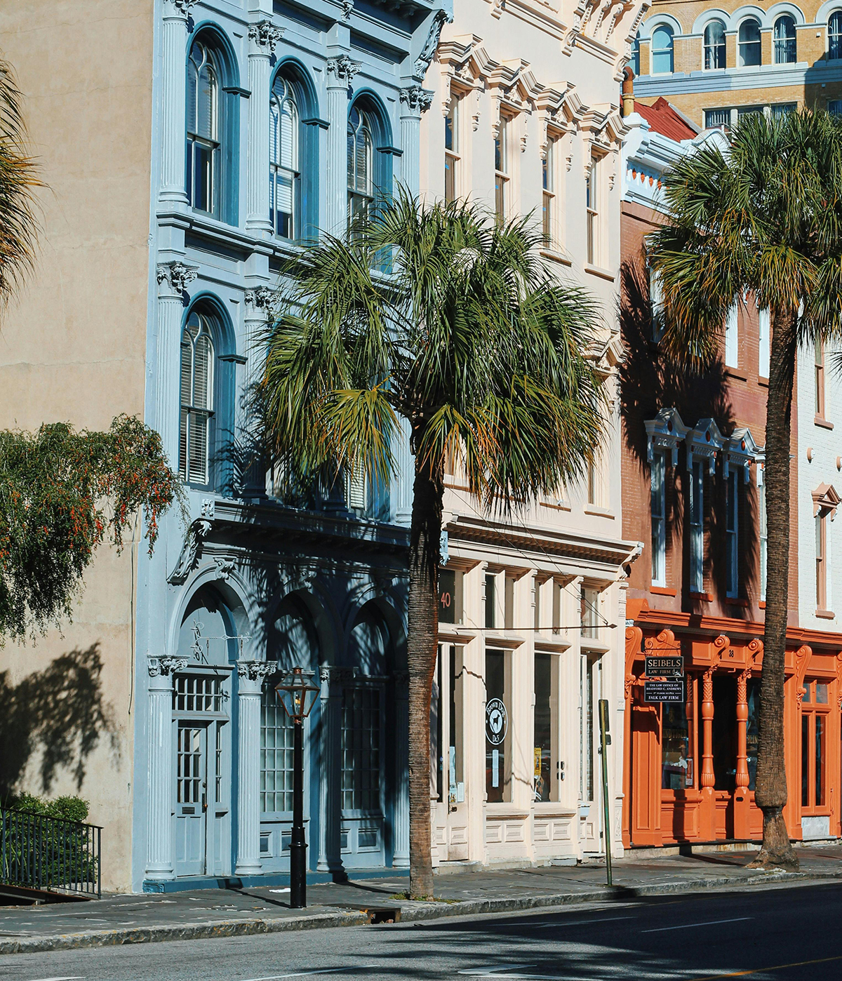 Historic buildings in Charleston, SC, featuring blue and peach facades, palm trees, and a streetlamp, representing the local community and atmosphere for addiction recovery support.